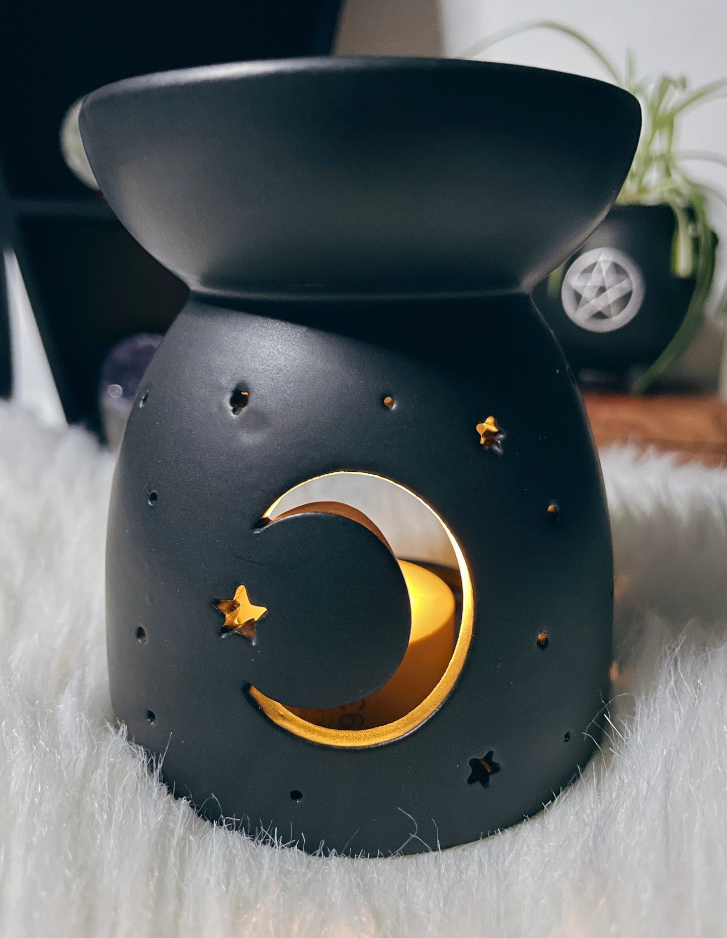 A black ceramic oil burner / wax melt burner with a crescent moon design cut out.