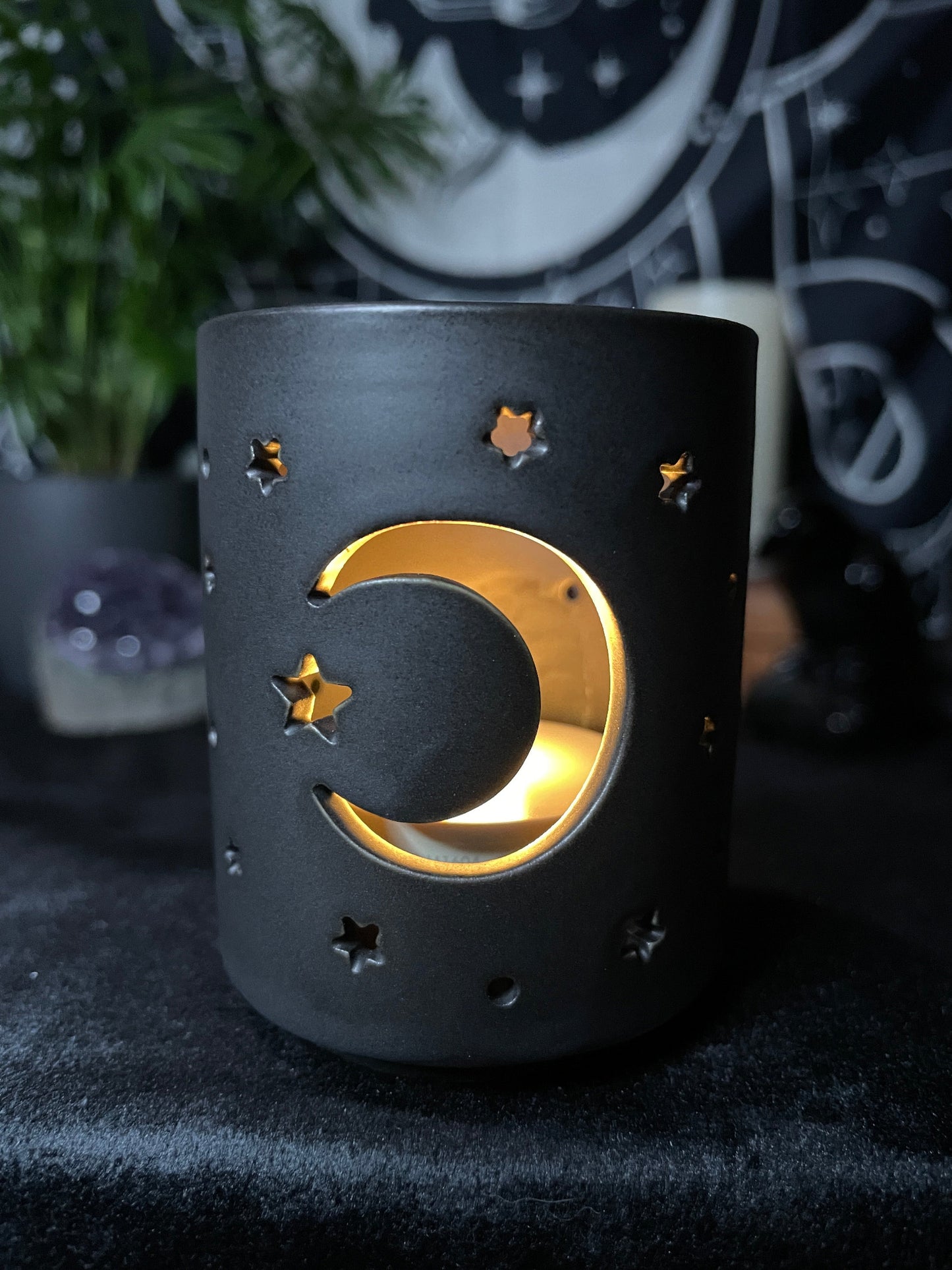 A black ceramic tealight holder with a crescent moon design cut out.