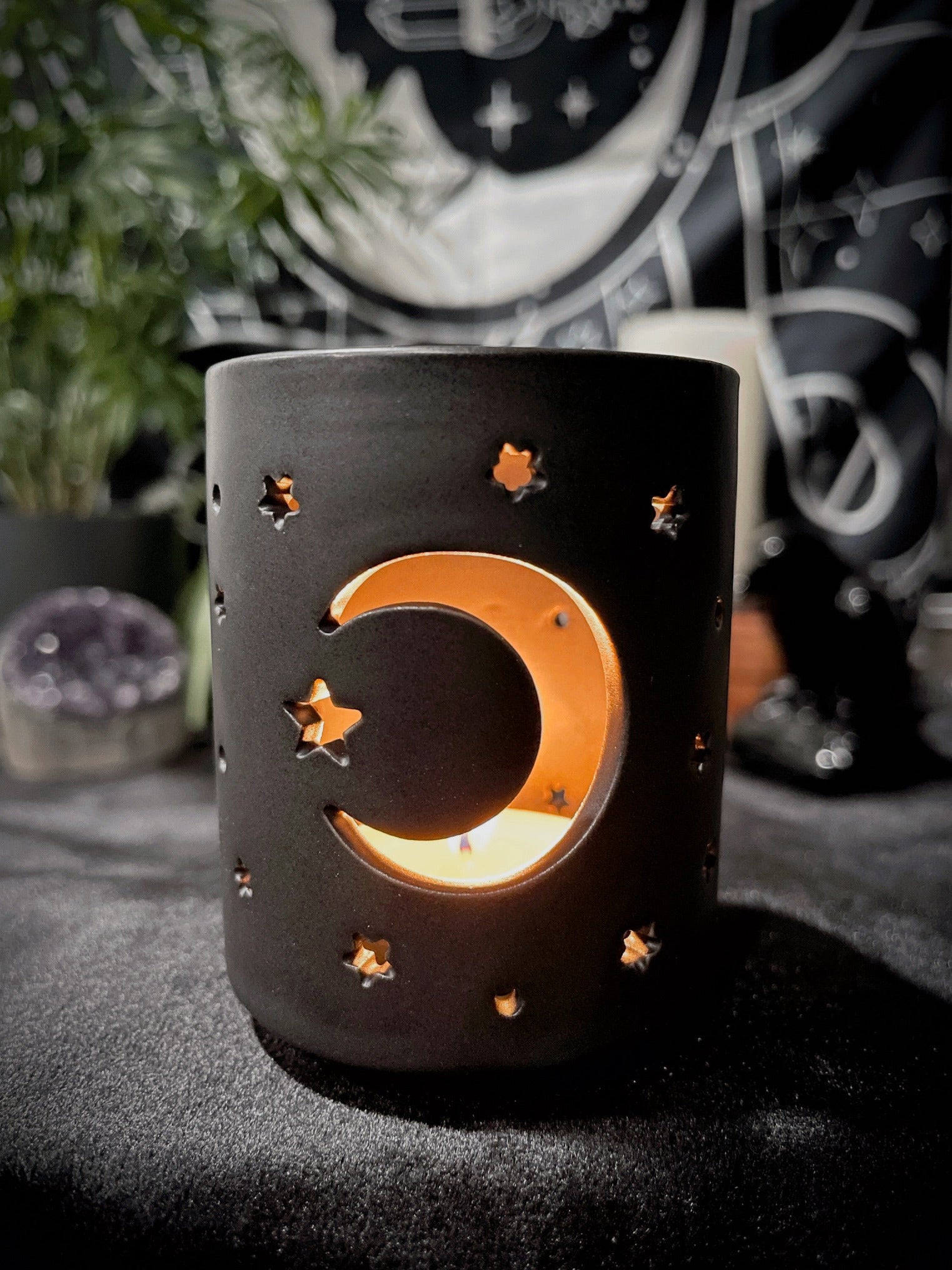 A black ceramic tealight holder with a crescent moon design cut out.