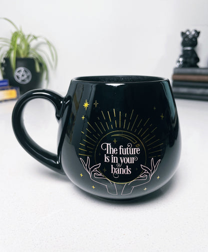 Pictured is a black ceramic mug with colour-changing words that say "The future is in your hands".