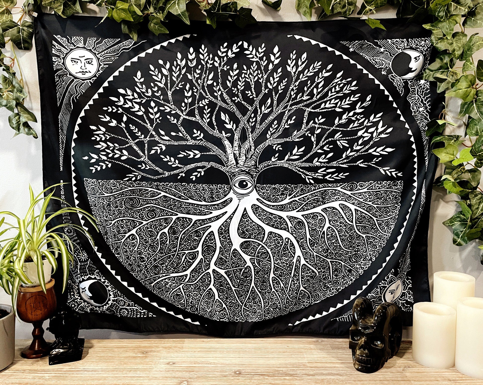 Pictured is a large wall tapestry with a black background and a tree of life printed in white on it.