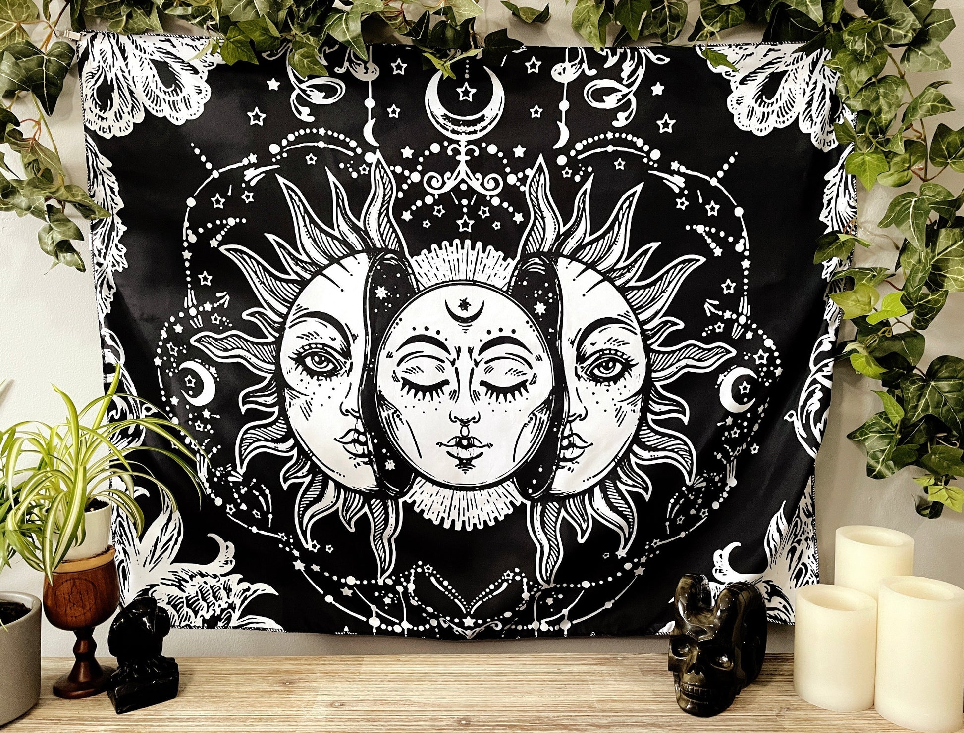Pictured is a large wall tapestry with a black background and a large moon inside a sun printed in white on it.