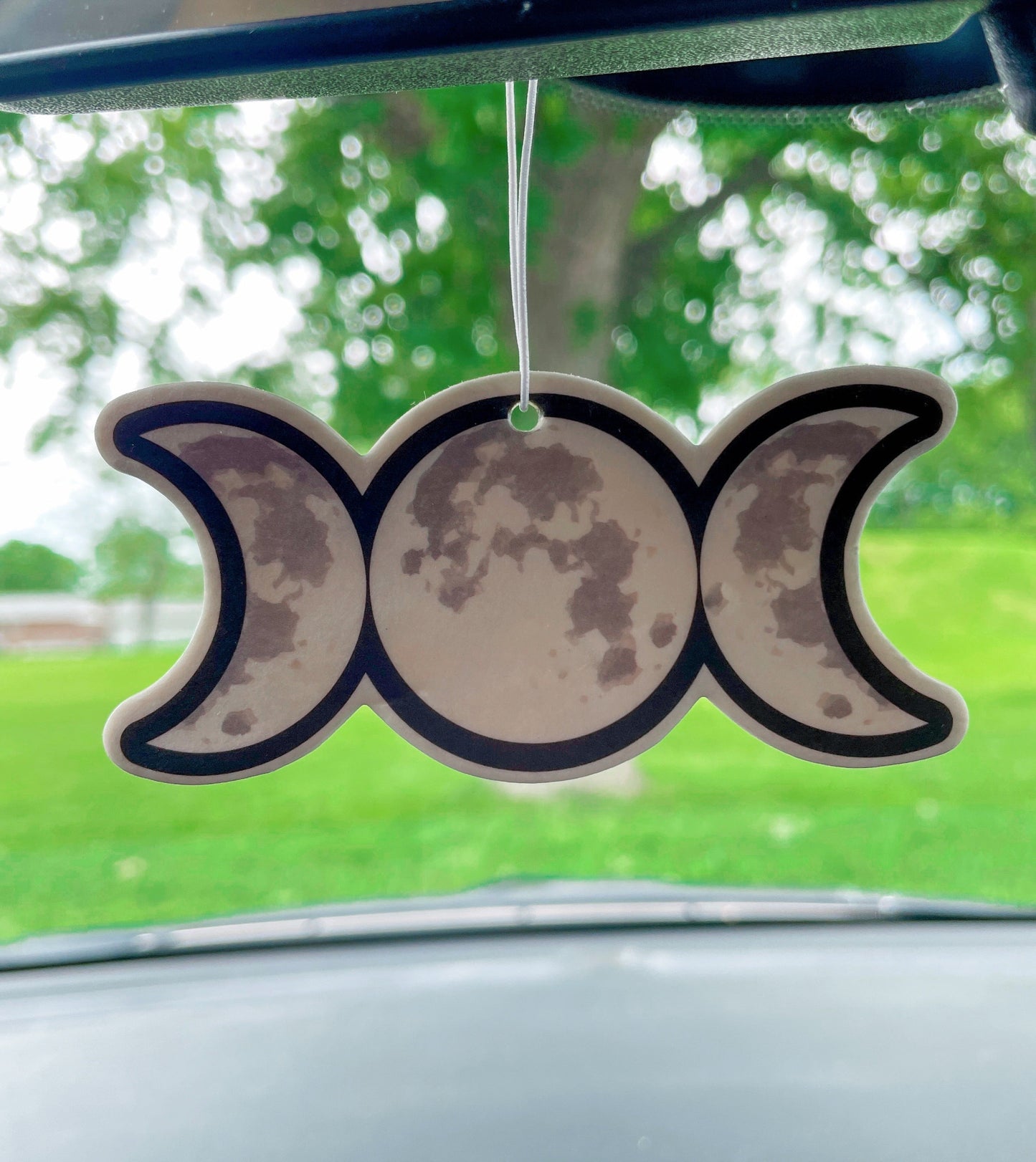 Pictured is an air freshener in the shape of a triple moon symbol