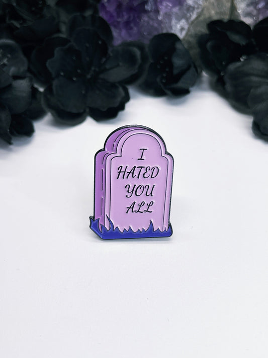 An image of an enamel pin featuring a purple tombstone with the words "I Hated You All" written in black letters. The pin is a bold and edgy accessory that celebrates individuality and nonconformity, and is perfect for anyone who wants to make a statement and stand out from the crowd.