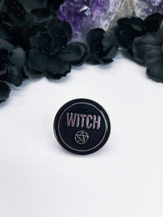Pictured is an enamel pin that says "witch".
