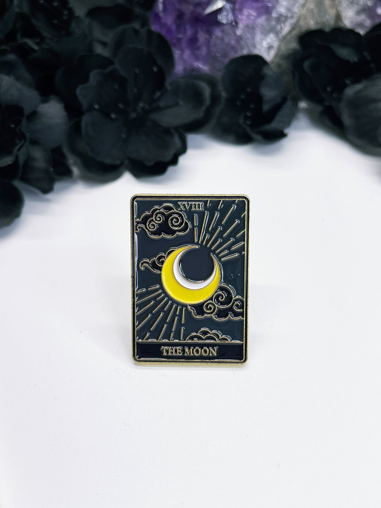  An enamel pin featuring a tarot card with a crescent moon on it, the card is "The Moon."
