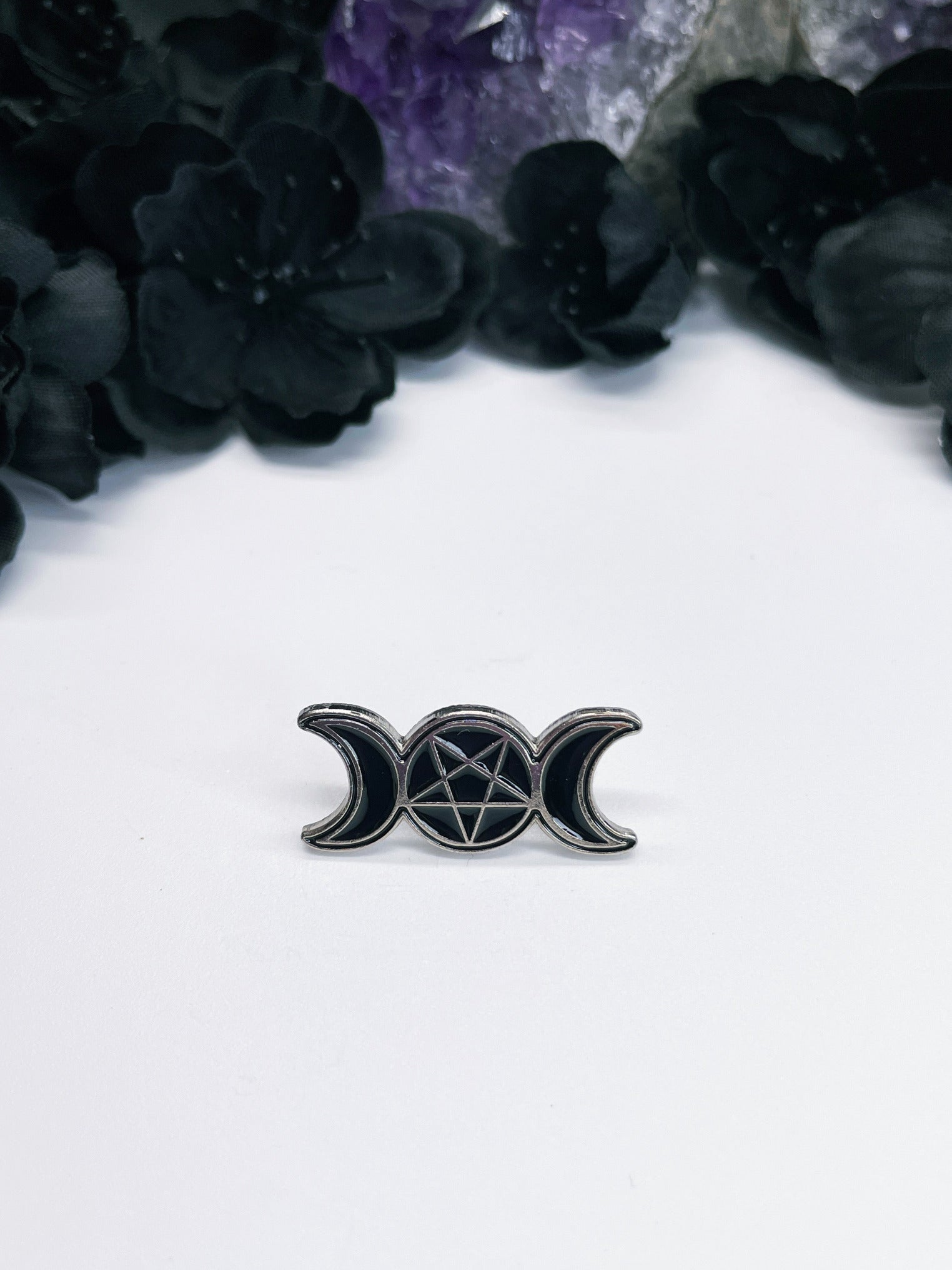 Pictured is an enamel pin of a triple moon symbol