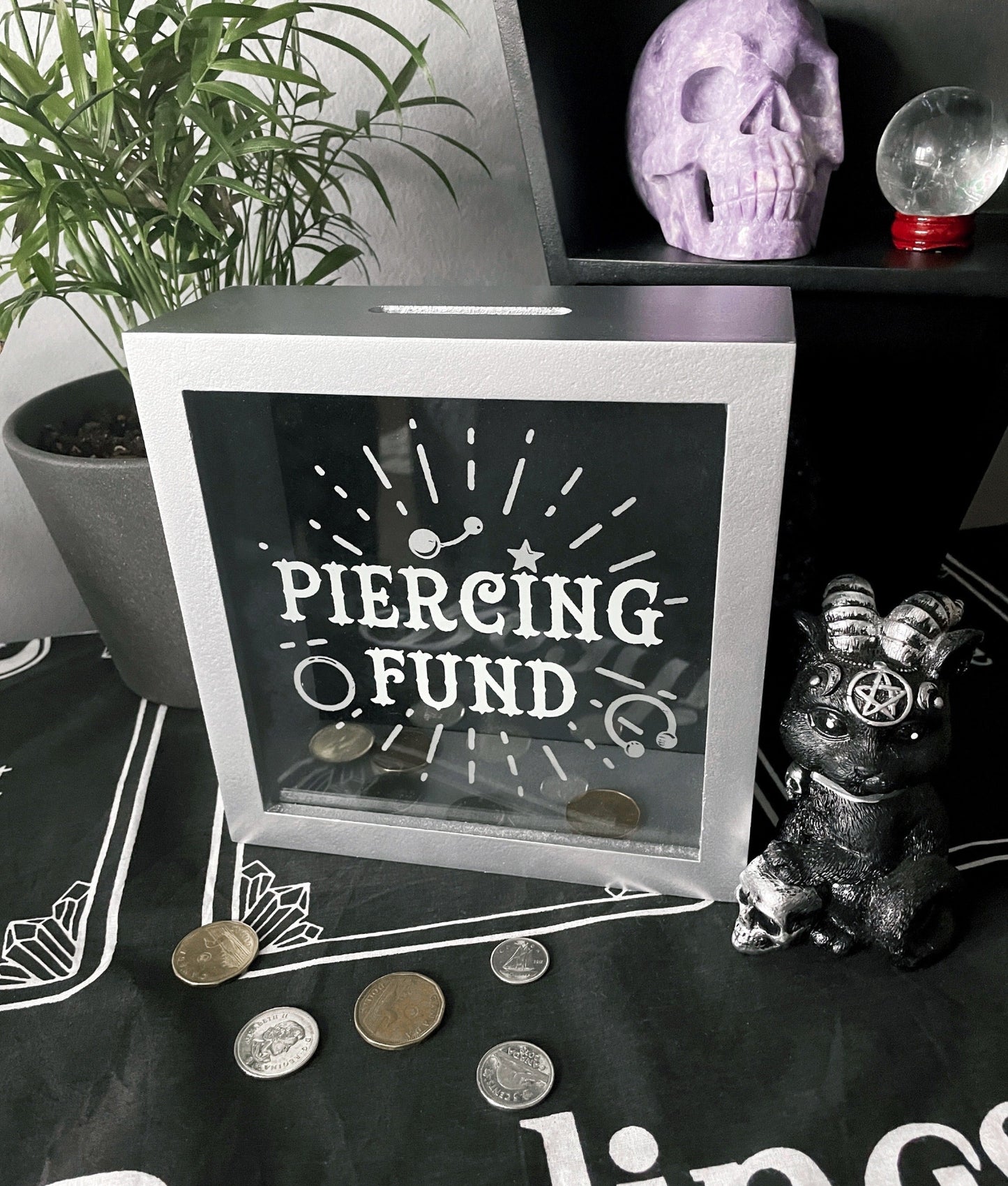 Pictured is a piggy bank or money box with the words "piercing fund" on the front.