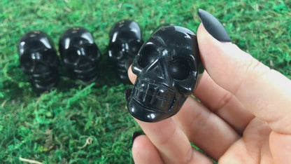 Pictured are various two inch skulls carved out of black obsidian.
