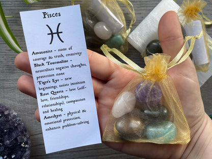 An image of a collection of tumbled stones in an organza bag. To the side is a piece of paper that describes what each tumbled stone's metaphysical properties are.